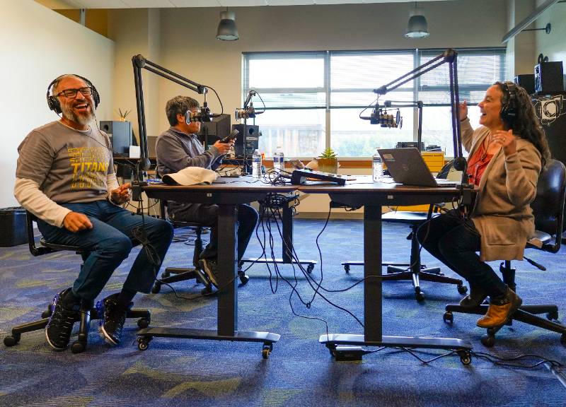 a group of people sit around a table with podcast equipment