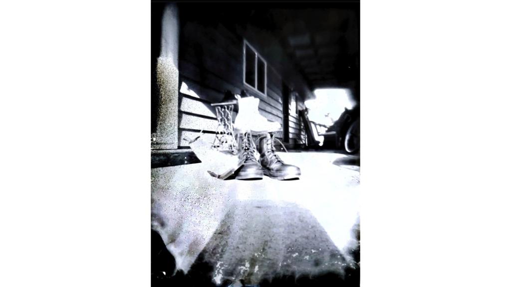 Black and white photo of boots on porch