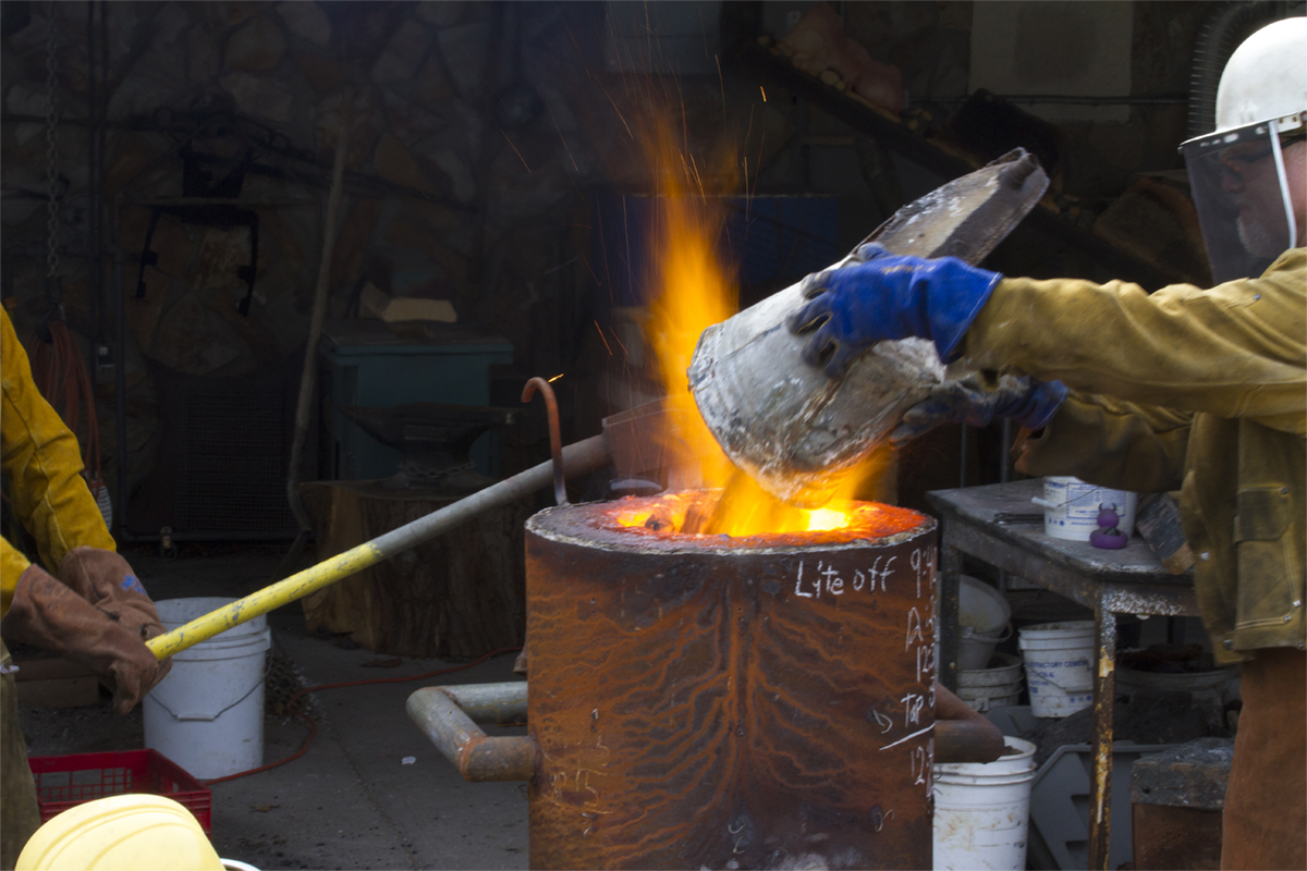 Iron pour with fire shooting up from the crucible