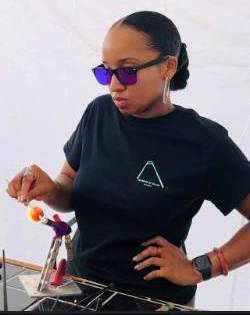 A headshot of Emily blowing glass