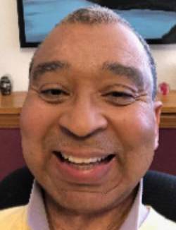 A headshot of JW Harrington smiling with a painting in the background