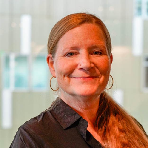 Smiling female with long hair on left shoulder in black shirt.