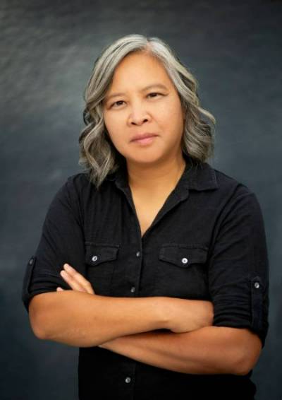 Headshot of Putsata Reang, arms folded in a black dress shirt.