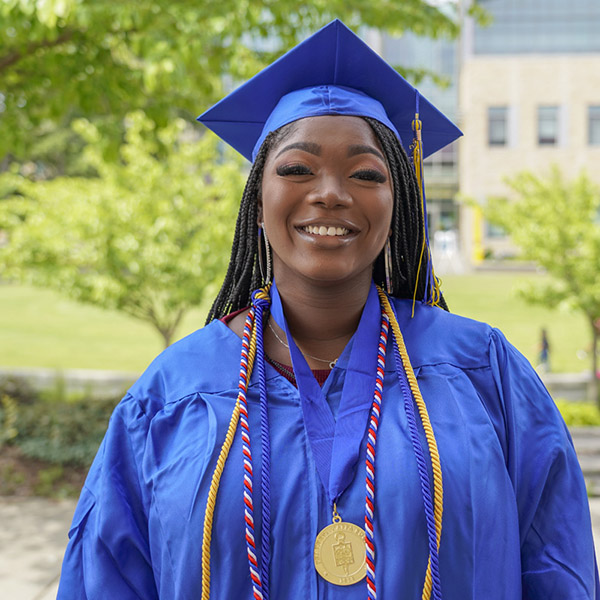 Woman in cap and gown with honor cords and ptk medal