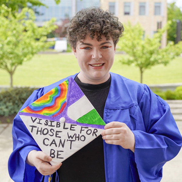 woman holding grad hat that says visible for those who can't be