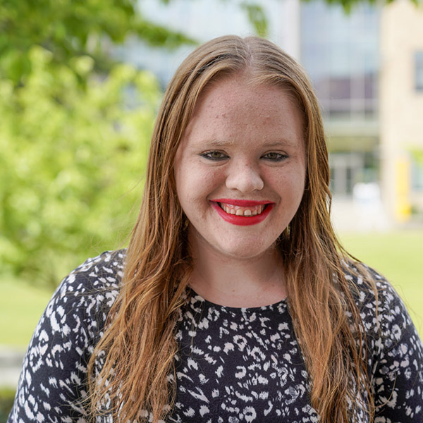 woman with long hair and pattered shirt smiling