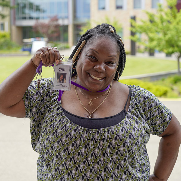 woman with braided hair holding up lanyard with ID smiling 