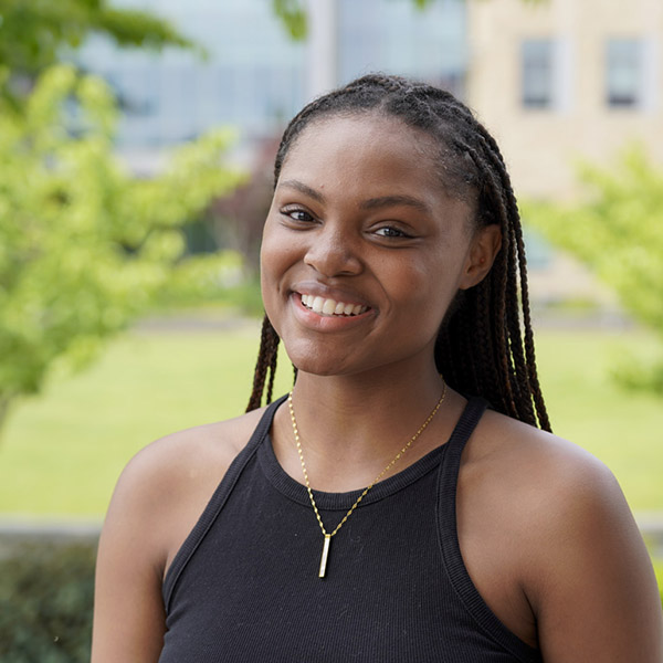 Woman with long braided hair and a black tank top smiling 