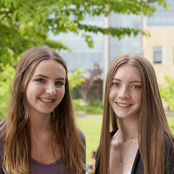 two young women with long hair smiling