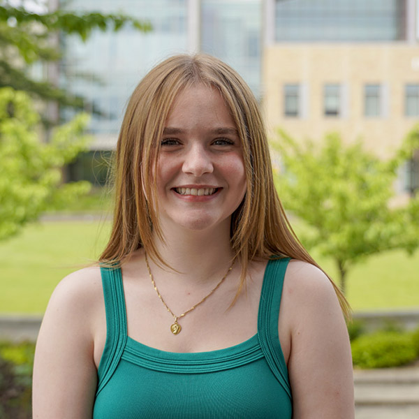 Young woman with long hair and green tank top smiling