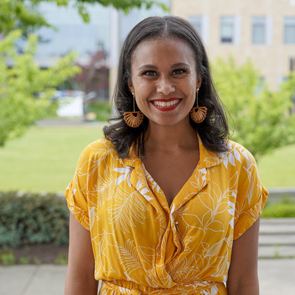 Woman in a yellow dress with yellow earrings smiling