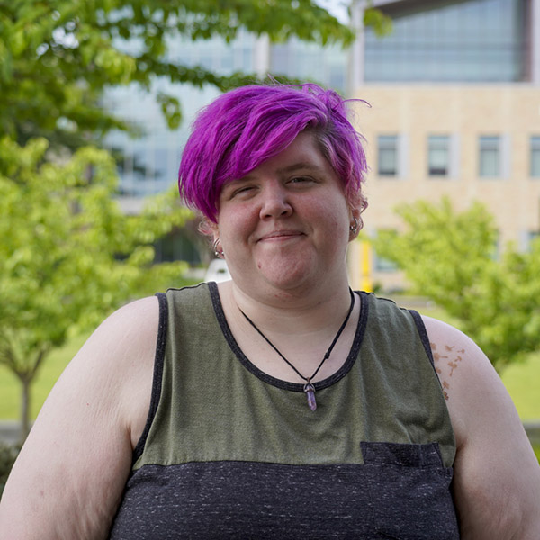 Woman with short purple hair in tank top smiling