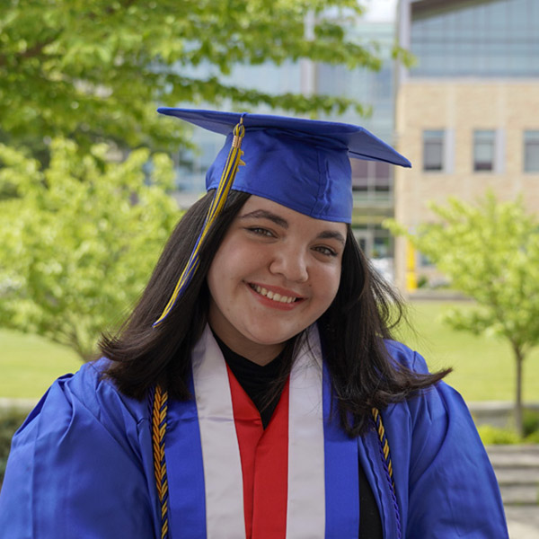 women in commencement regalia with red white and blue stole smiling