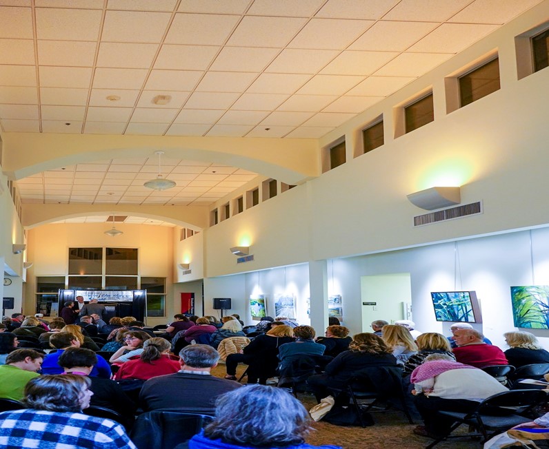 people seated watching conference speaker