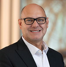 Keith Sprague Smiling white mle with black glasses and a black sport coat.