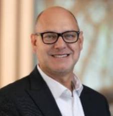 Smiling white mle with black glasses and a black sport coat.