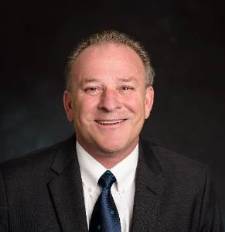 portrait photo of a man in a suit smiling