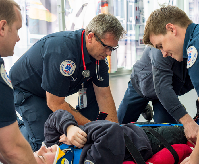 A group of paramedic trainees lift a volunteer