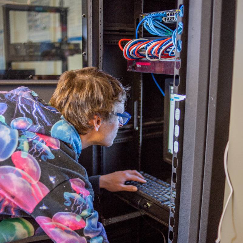a student reaches into a network hub in class