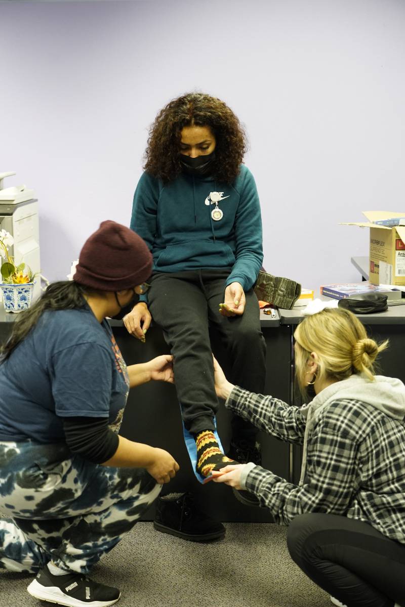 A student is having her ankle braced by her peers