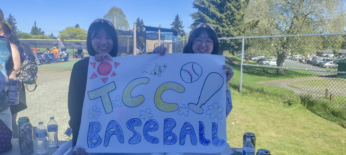 two students holding up a TCC Baseball sign. 