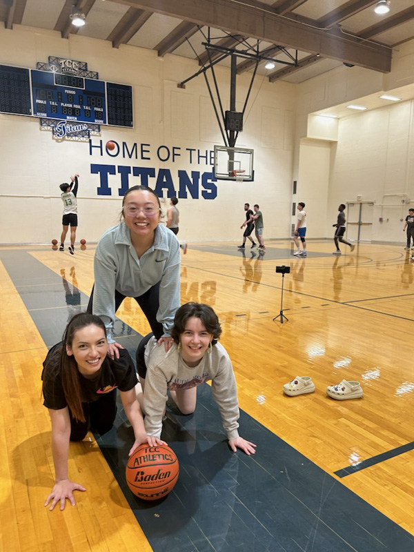 three students forming a human pyramid in the TCC Gym. 