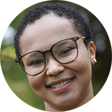 A woman with short hair and glasses smiling. 