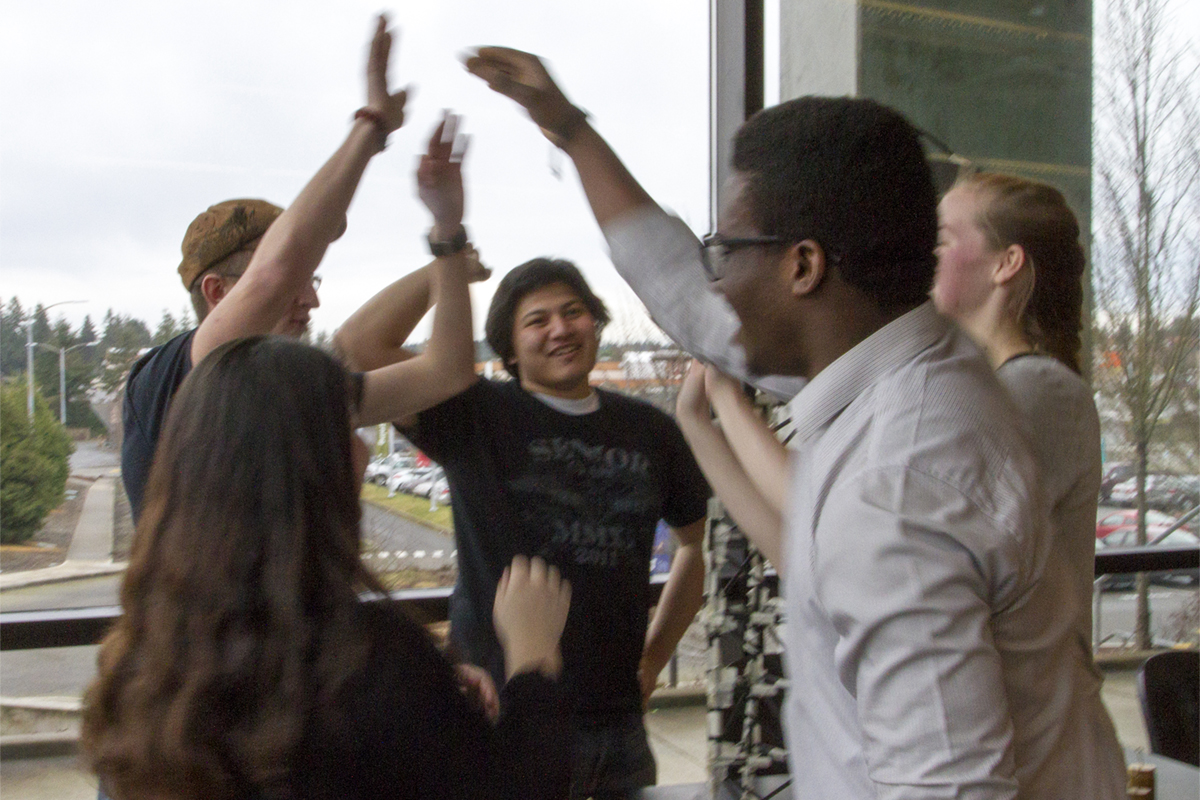 A group of students high fiving around a lab table