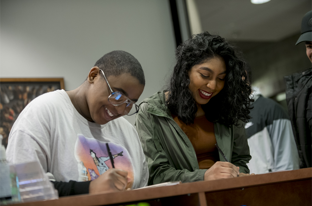 Two students at a desk writing